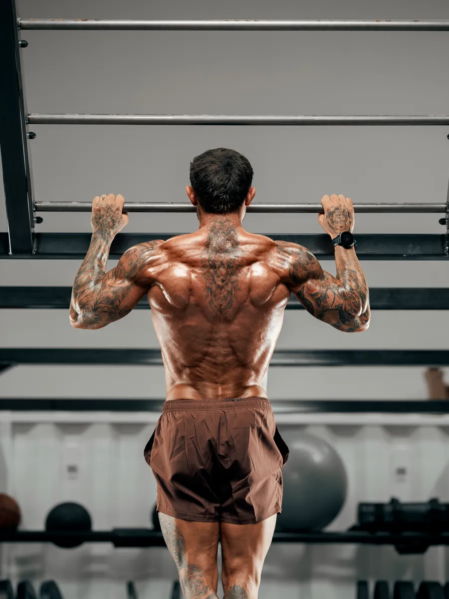 Hanging from a pull-up bar, back view showing the back tattoo